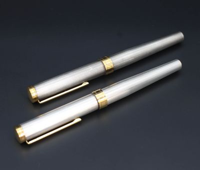 deux stylos à plume argentés et dorés posés sur une surface noire