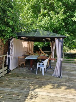 a gazebo on a wooden deck with a table and chairs