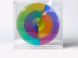 a multicolored object in a clear box on a white surface