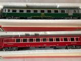 two red and green trains in boxes on a table