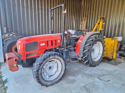 un tracteur rouge garé devant un bâtiment