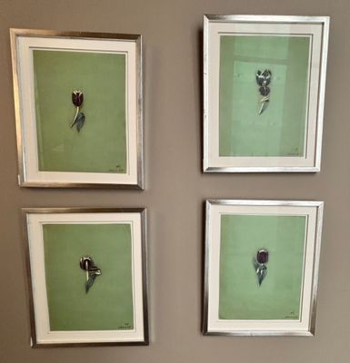 trois photos de fleurs encadrées sont accrochées au mur au-dessus des toilettes
