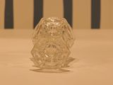a glass vase sitting on a table with a striped chair in the background