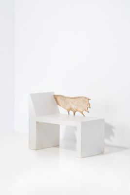un banc blanc sur lequel est posé un animal en bois, dans une pièce blanche