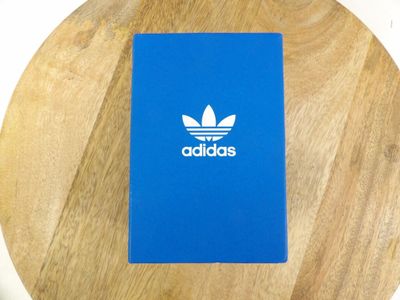 blue notebook with white adidas logo on it sitting on a wooden table