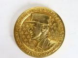 an image of a gold medal with a man wearing a top hat