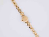 a close up of a gold bracelet on a white surface