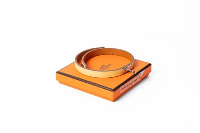 une boîte orange sur laquelle est posé un bracelet, posée sur une surface blanche
