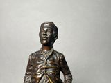 a bronze statue of a man standing with his hands in his pockets