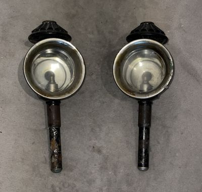 pair of stainless steel bowls with handles on a gray surface