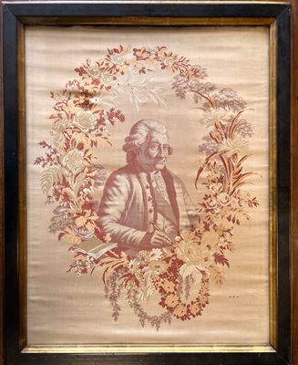an old picture of a man in a turban sitting in front of a wreath of flowers