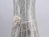 the back of a woman ' s white dress with a flower on it