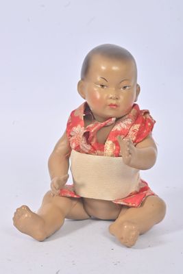 une petite poupée représentant un bébé assis par terre