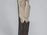 a statue of a woman with a hat on top of a wooden pole
