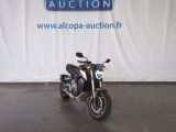 moto garée devant un panneau annonçant une vente aux enchères de motos