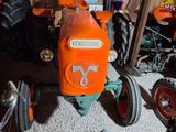 an orange tractor sitting in a garage next to other tractors