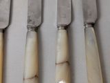 four knives are lined up on top of each other on a table