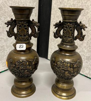 une paire de vases anciens en laiton posés sur une table devant un mur