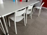 a white table with four chairs and a laptop on it