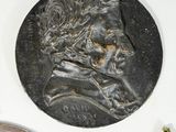 three bronze medallions of a man and a woman on a white surface
