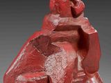 a red sculpture of a man sitting on top of a chair