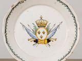 a white plate with a gold crown and two swords on it