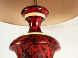 a red lamp that is on a table with a lamp shade