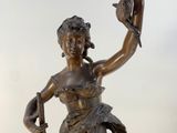 bronze statue of a woman holding a bird on a marble base