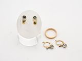 deux bagues en or et une paire de boucles d'oreilles posées sur une table blanche