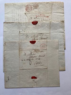 trois feuilles de papier sur lesquelles figurent des inscriptions à l'encre rouge, posées sur une table