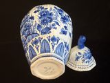 un vase bleu et blanc et une clochette posés sur une table noire