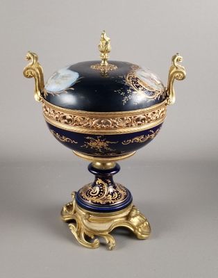 un vase bleu et or posé sur un socle, sur une surface grise