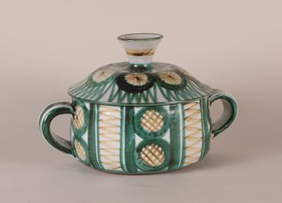 a green and white bowl with a lid on a table