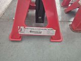 a red stand with a sign on it on the sidewalk