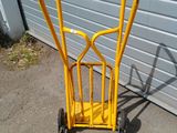 a yellow hand truck that is parked in front of a garage