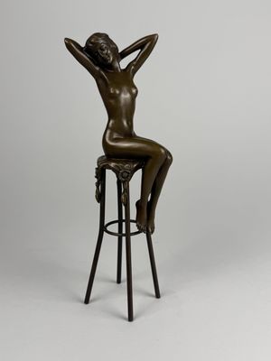 a bronze statue of a woman sitting on a stool