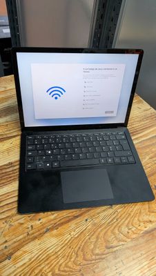 un ordinateur portable posé sur une table en bois, avec le symbole du Wi-Fi affiché à l'écran