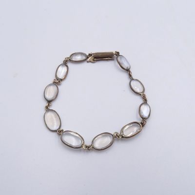 un bracelet en or orné de perles de verre blanches sur fond blanc