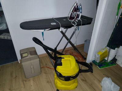 a yellow vacuum cleaner and a black ironing board in a room