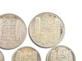six silver coins of different shapes and sizes on a white surface