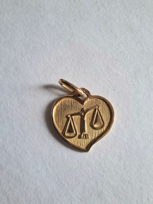 a gold heart shaped charm with scales on it