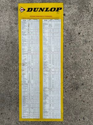 the back of a yellow and white sign on a concrete wall