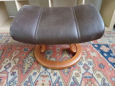 un pouf en cuir marron posé sur un tapis au sol
