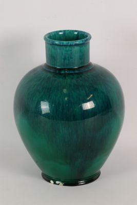 un vase vert posé sur une surface blanche