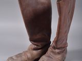 une paire de bottes en cuir marron posées sur une surface blanche