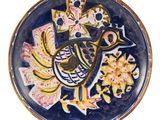 une assiette bleue et jaune décorée d'un oiseau et de fleurs