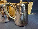 two silver pitchers sitting next to each other on a table