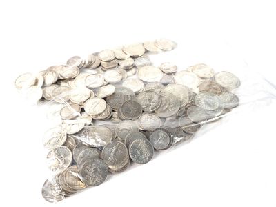 un sac rempli de pièces d'argent posé sur une surface blanche