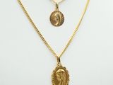 a gold necklace with a lion head and a coin on a mannequin