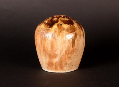 a brown and white vase sitting on a black surface